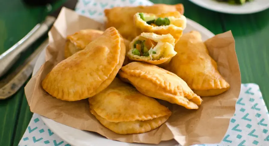 Panzerotti al forno dorati e ripieni di verdure, serviti su carta da forno.
