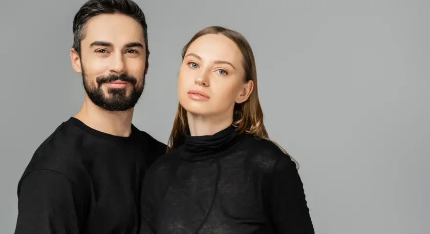Para, która wygląda jakby mogła nosić ubrania unisex. On z brodą, ona z długimi włosami, oboje w czerni.