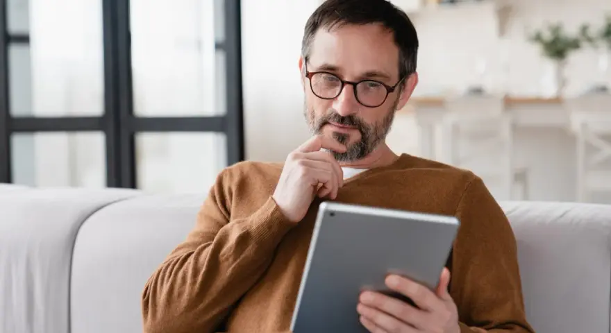 Mann sitzt nachdenklich auf Sofa, sein Samsung Tablet geht nicht mehr an.