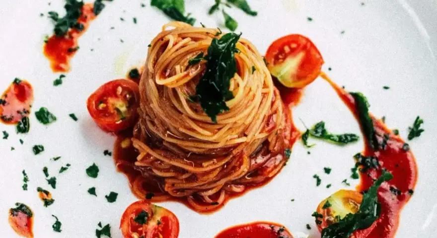 Eleganckie spaghetti bez mięsa, podane z sosem pomidorowym, świeżymi pomidorkami koktajlowymi i posypane ziołami.