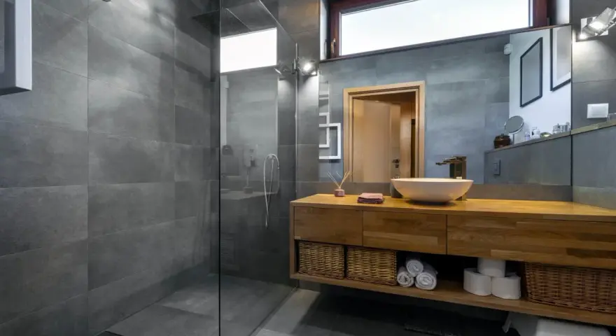Salle de bain moderne avec douche à l'italienne, carrelage gris, meuble en bois et vasque. Le pose carrelage douche italienne est impeccable.