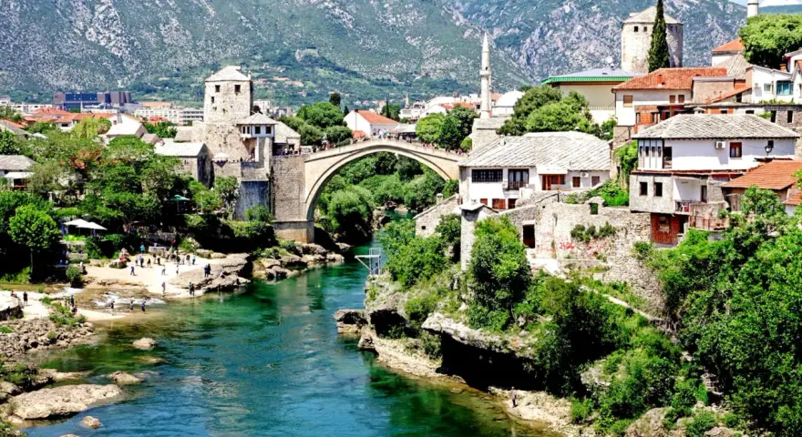 Mostar, Bośnia i Hercegowina. Tłumy ludzi spacerują po Starym Moście, a turkusowa rzeka Neretwa płynie poniżej. Czy Bośnia i Hercegowina jest bezpieczna? Tak, to piękny kraj.