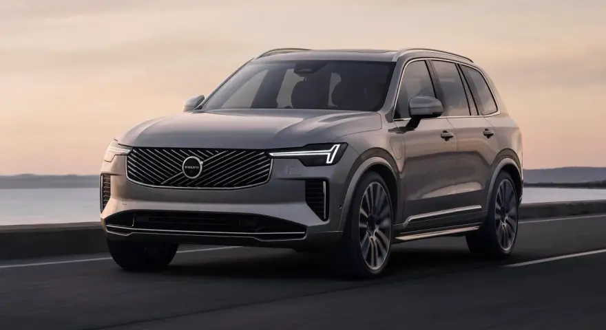 Elegancki, szary Volvo XC90 T8 sunie po drodze przy zachodzie słońca.