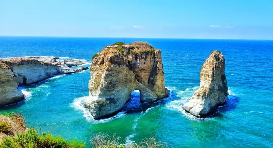 The Raouché sea stacks, iconic natural landmarks and historical sites in Lebanon, stand majestically against the bright blue Mediterranean Sea.