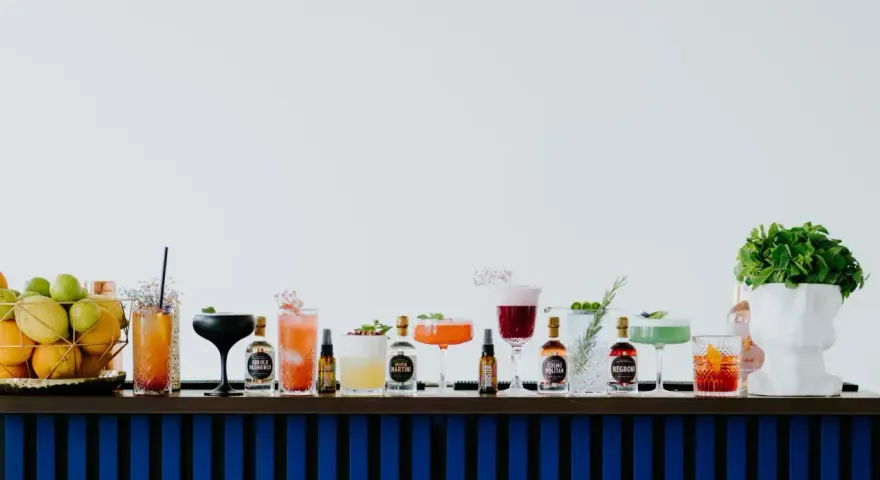 Kolorowe drinki z adwokatem i buteleczki z alkoholami na barze.