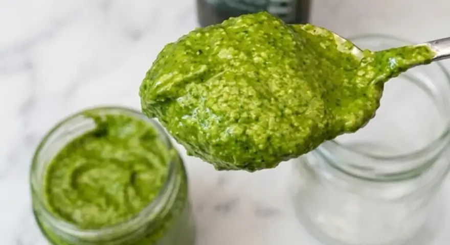 Un cucchiaio di fresco pesto genovese, pronto per essere messo in un vasetto. La ricetta pesto genovese frullatore è facile e veloce.