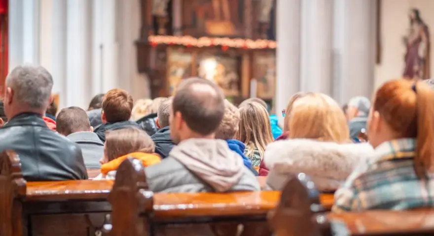 Ludzie siedzą w kościele, słuchając kazania. Wszyscy otrzymują błogosławieństwo, składając życzenia na bierzmowanie.