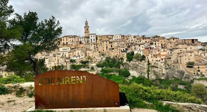 Cartel de "Bocairent" con el pueblo al fondo. Descubre qué ver en Bocairent, un pueblo colgado en la roca.