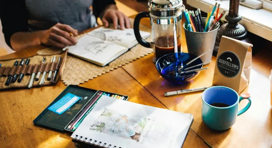 Kreative Inspiration am **cafe impuls**: Skizzenbuch, Stifte, Kaffee und eine Tasse laden zum Malen ein.