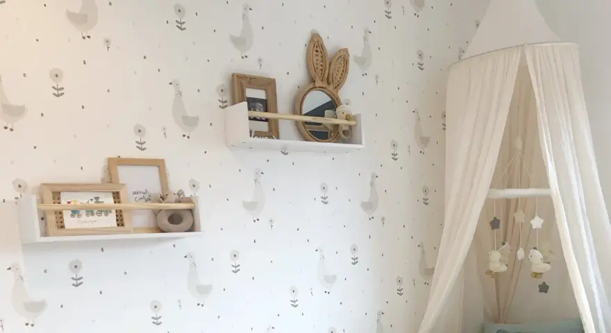Habitaciones con papel pintado y pintura de patitos y flores. Un dosel de cama blanco cuelga sobre una cuna.