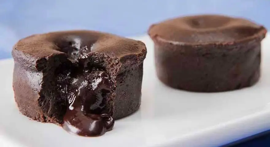 Fondant au chocolat coulant, une gourmandise inspirée de la recette de Cyril Lignac. Le cœur liquide de chocolat fond sur la plaque blanche.