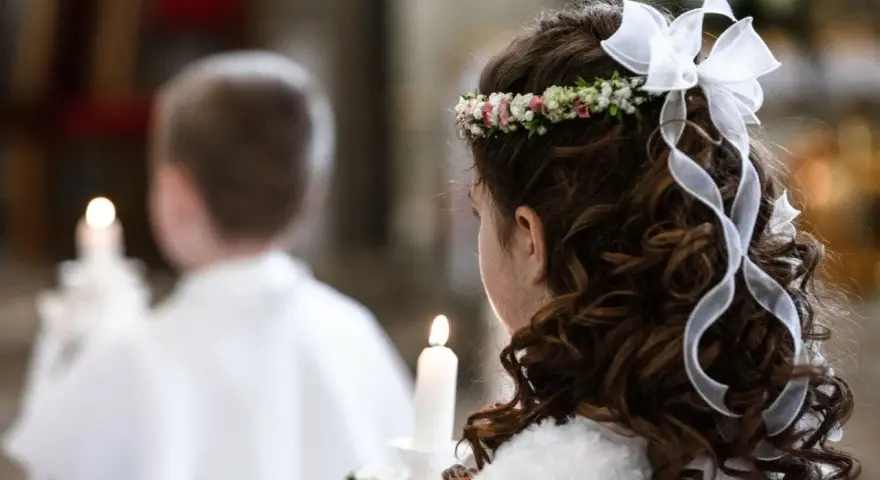 Dziewczynka z wiankiem na głowie i wstążkami we włosach trzyma świecę. Obok niej chłopiec, też z zapaloną świecą. To ważny dzień, biały tydzień.