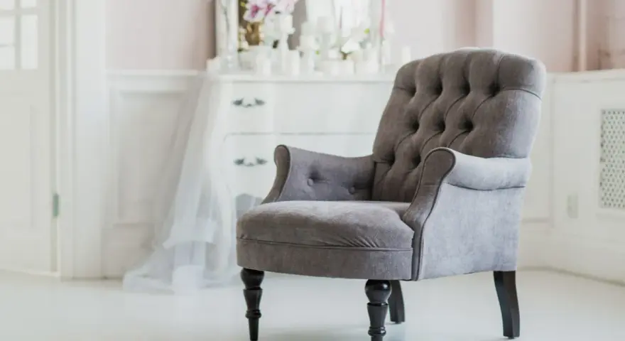 Elegante sillón gris con botones, ideal para un tocador. ¿Cuánto vale tapizar una silla así?