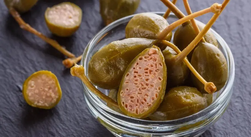 Cucunci sotto sale in una ciotola di vetro, alcuni tagliati a metà rivelano la loro polpa interna.