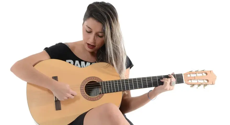 Kobieta gra na gitarze, nucąc stare piosenki country.