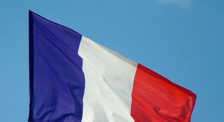 La bandera de Francia ondea con orgullo contra un cielo azul claro.