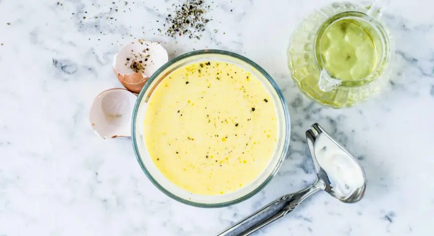 Zutaten für eine cremige french dressing: Eierschalen, Pfeffer, Öl und eine Schüssel mit der fertigen Soße.