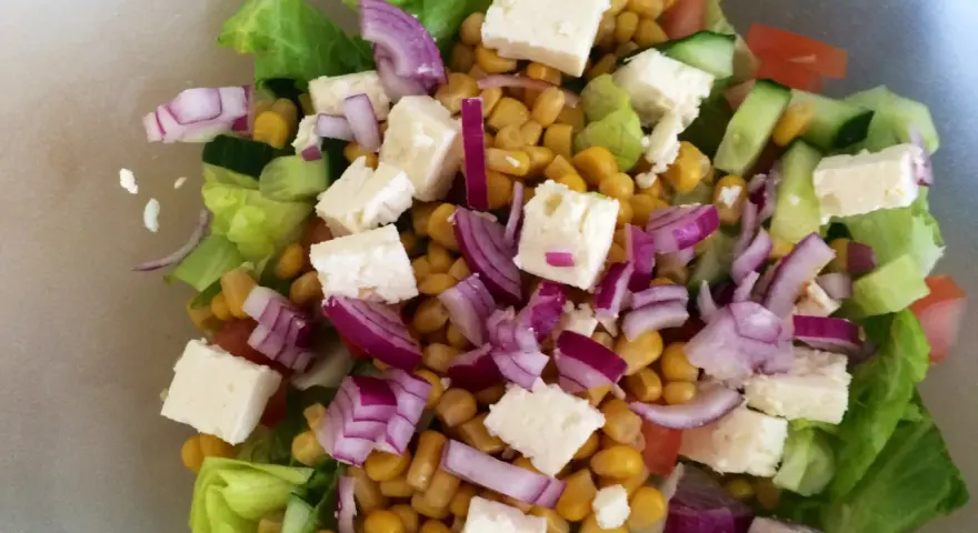 En fräsch sallad med sallad, majs, fetaost, rödlök och gurka. Perfekt för ett lätt och näringsrikt deffa kostschema.