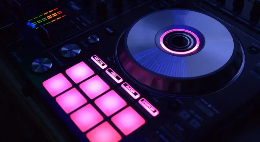 DJ kontroler z podświetlanymi na różowo padami i świecącym na niebiesko talerzem. Idealny do tworzenia muzyki, np. dubstep co to za gatunek?