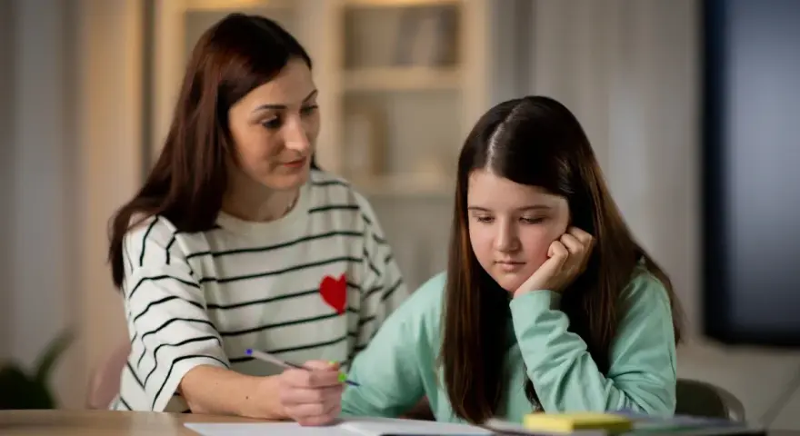 Mama tłumaczy córce, jak działa edukacja domowa. Dziewczynka zamyślona, opiera głowę na dłoni.