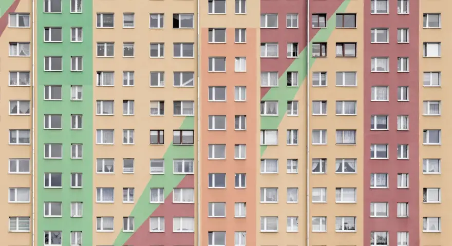 Wielopiętrowy blok mieszkalny w kolorach pastelowych. Szukasz informacji, jak wynająć mieszkanie komunalne?