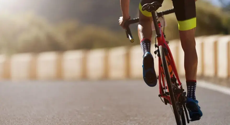 Cyclist in neon-accented shorts and polka-dot socks powering up a hill, embodying a dedicated sprint workout plan.