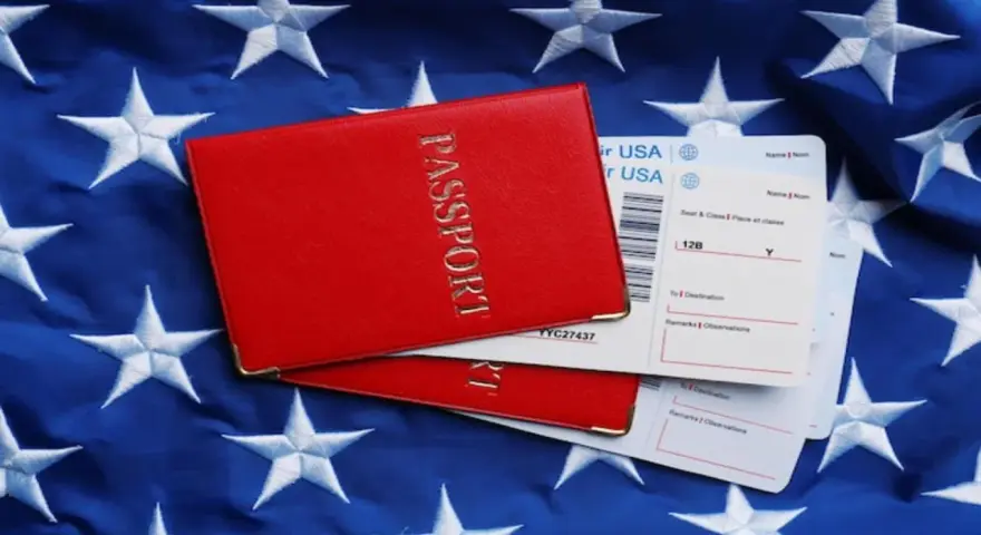 Czerwony paszport i bilety lotnicze na tle flagi USA. Zastanawiasz się, ile kosztuje bilet do USA w dwie strony?