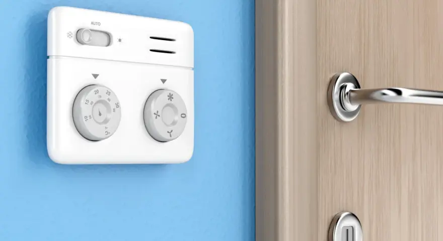 Termostato bianco su muro blu, parte di sistemi termoregolazione evoluti per un comfort ottimale. Manopole per impostare la temperatura.