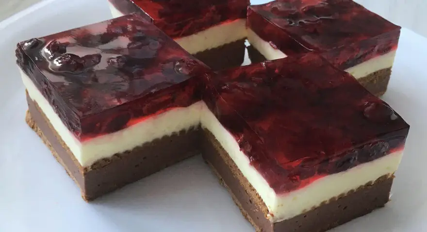 Proste ciasto z serkiem mascarpone i galaretką wiśniową, ułożone na białym talerzu.