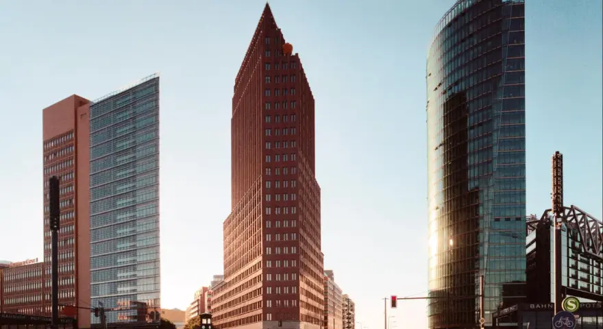 Moderne Hochhäuser am Potsdamer Platz in Berlin, darunter der spitze roter Backsteinbau, der an den schnellsten Fahrstuhl Berlins erinnert.