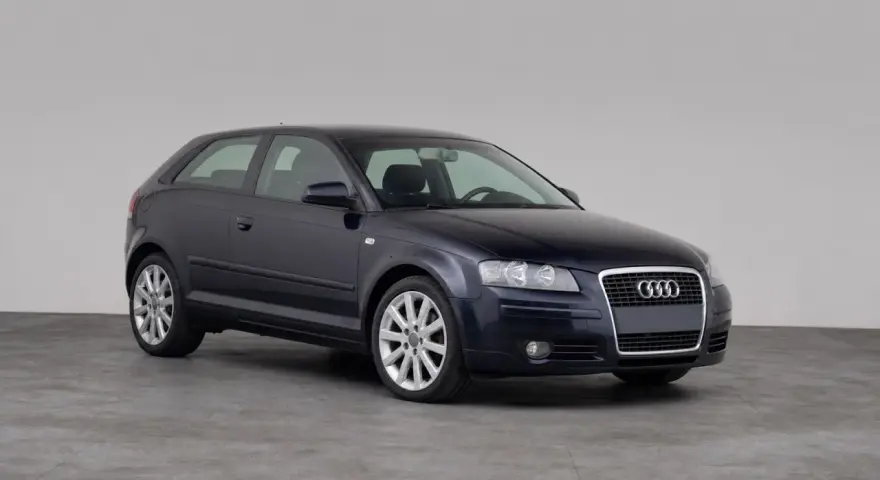 Dunkelblauer Audi A3 1.9 TDI Dreitürer steht auf grauem Boden vor hellem Hintergrund.
