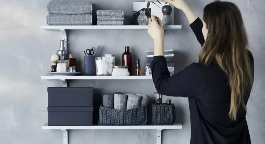 Idee mensole ingresso: organizzazione bagno con asciugamani grigi, scatole e cestini in maglia.