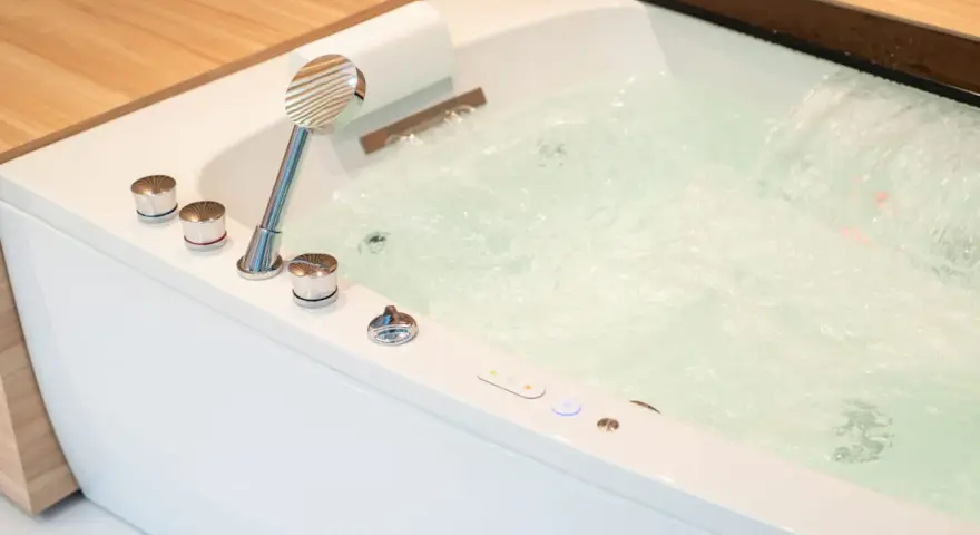 Bain bouillonnant avec jets d'eau et douchette chromée, prêt pour un moment de détente dans ce spa balnéo.