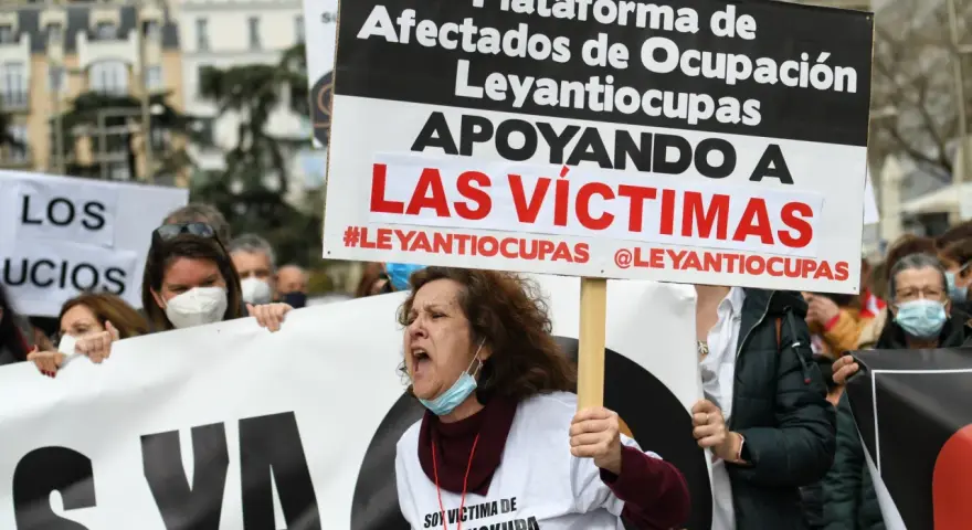 Manifestantes protestan contra la ocupación de vivienda habitual. Una mujer grita, portando un cartel que apoya a las víctimas de #Leyantiocupas.