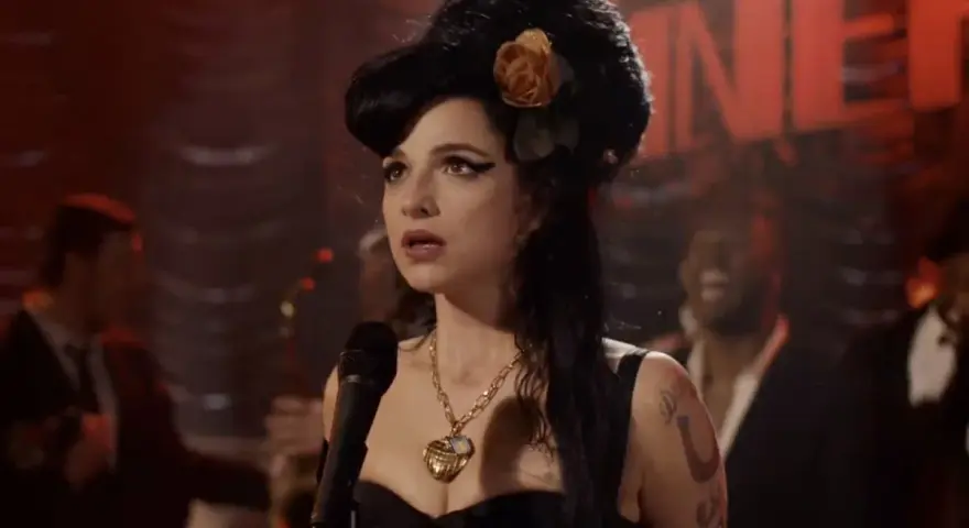 Aktorka wcielająca się w Amy Winehouse na scenie, w charakterystycznej fryzurze i z naszyjnikiem. Scena przypomina fragmenty z filmów o jej życiu.