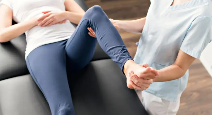 Fizjoterapeuta delikatnie masuje stopę pacjentki, która leży na kozetce. Czy rehabilitacja pomaga? Tak, to klucz do powrotu do zdrowia.