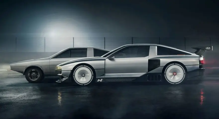 Dwa samochody Hyundai N Vision 74 stoją obok siebie na mokrej nawierzchni. Jeden jest bardziej klasyczny, drugi futurystyczny.