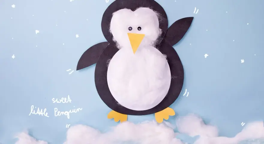 Ein süßer kleiner Pinguin, gebastelt aus Papier und Watte, steht auf Wolken.