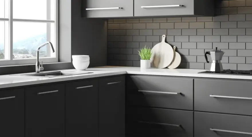 Une cuisine moderne et épurée, idéale pour rénover sa cuisine sans changer les meubles. Des placards sombres, un plan de travail blanc et un crédence en briques grises.