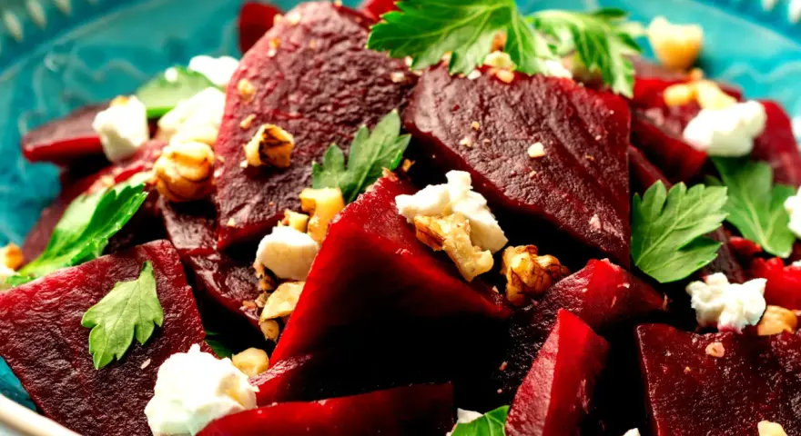 Ein köstlicher Rote Bete Feta Salat mit Nüssen und frischer Petersilie, serviert in einer blauen Schüssel.