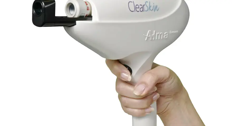 Dłoń trzymająca białe urządzenie laserowe Alma Harmony ClearSkin, gotowe do zabiegu.