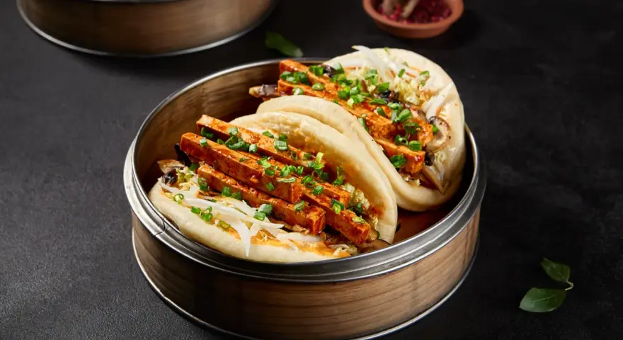 Pierożki baozi z tofu i warzywami, podane w bambusowym parowniku.