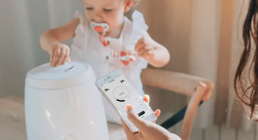 Niña interactúa con humidificador mientras una mano controla la app para humidificar el ambiente.