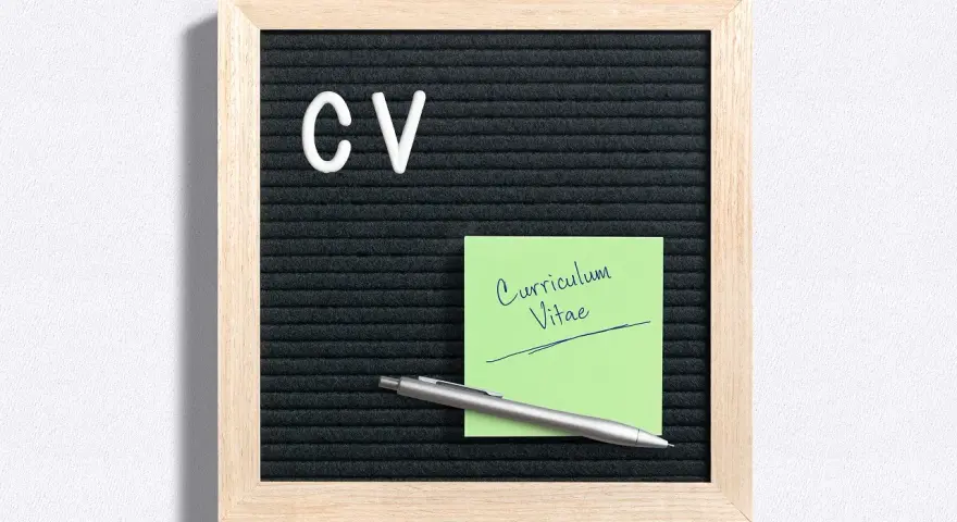 Tablica z literami "CV" i zielona karteczka z napisem "Curriculum Vitae". Idealne do przygotowania CV po niemiecku.
