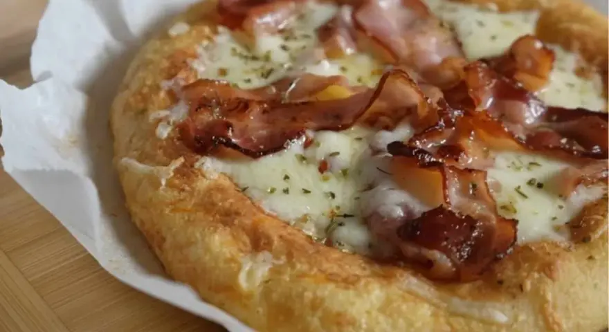 Pyszna keto pizza na drożdżach z chrupiącym boczkiem i ciągnącym serem. Idealna na szybki posiłek.