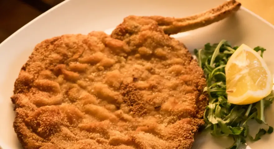 Cotolette al forno dorate e croccanti, servite con rucola fresca e una fetta di limone.