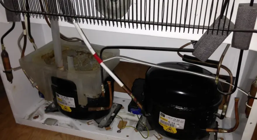 Kylskåpets kompressorer och kondensor. Det låter som en borr när kylskåpet går.