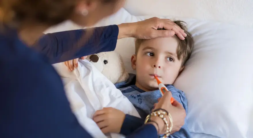 Chłopiec leży w łóżku, mama mierzy mu temperaturę. Znowu choruje, to już drugi raz w tym miesiącu.