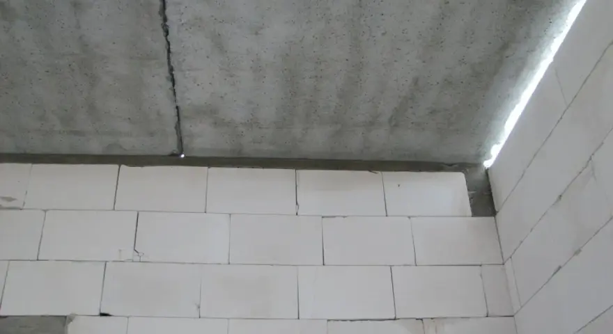 Betonowy strop z widocznym pęknięciem nad ścianą z białych pustaków.