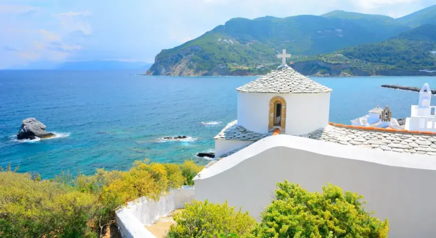 Malownicza zatoka i białe kościółki na wzgórzu. Idealne miejsce na skopelos wakacje.